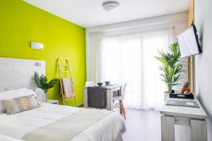 a bedroom with green walls and a bed and a desk at Dunas Club - Hotel & Apartamentos in Corralejo