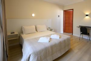a bedroom with a bed with two towels on it at Colonial Flat Hotel in Itapetininga