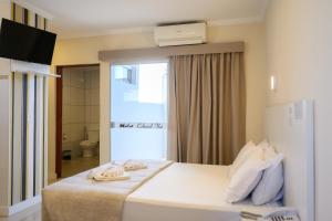 a hotel room with a bed with towels on it at Colonial Flat Hotel in Itapetininga