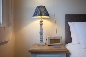a lamp on a table with a clock and a bed at ※ Stunning, Bath Townhouse, City Centre (AS) ※ in Bath
