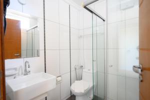 a white bathroom with a toilet and a sink at Colonial Flat Hotel in Itapetininga