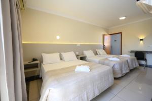 a hotel room with two beds with white sheets at Colonial Flat Hotel in Itapetininga