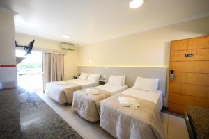 a hotel room with two beds with white sheets at Colonial Flat Hotel in Itapetininga
