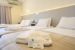 a hotel room with three beds with towels on them at Colonial Flat Hotel in Itapetininga