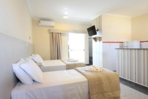 a hotel room with two beds and a tv at Colonial Flat Hotel in Itapetininga