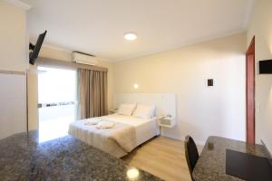 a hotel room with a bed and a table at Colonial Flat Hotel in Itapetininga