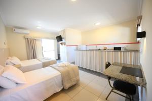 a hotel room with two beds and a desk at Colonial Flat Hotel in Itapetininga