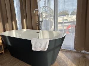 a black and white bath tub in a room with a window at Escale Royale Saint Jean de Losne 35' de Dijon House Boat sur l'eau in Saint-Jean-de-Losne