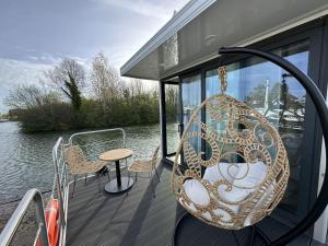 a porch with a swing and a table on a boat at Escale Royale Saint Jean de Losne 35' de Dijon House Boat sur l'eau in Saint-Jean-de-Losne