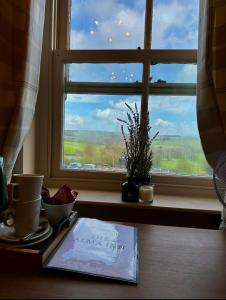 une fenêtre avec une table avec un livre et une assiette de nourriture dans l'établissement The Alma Inn, à Sowerby Bridge