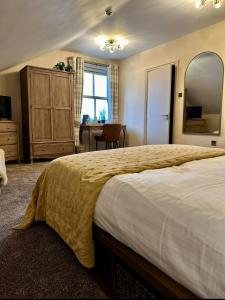 a bedroom with a large bed with a yellow blanket on it at The Alma Inn in Sowerby Bridge