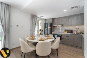 a kitchen and dining room with a table and chairs at Vogue Villa Near Golf/Ski Dubai/ Ibn Battuta Mall in Dubai