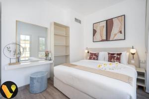 a white bedroom with a large bed and a mirror at Vogue Villa Near Golf/Ski Dubai/ Ibn Battuta Mall in Dubai