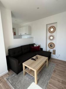 a living room with a black couch and a coffee table at Appartement aux portes de Paris in Ivry-sur-Seine