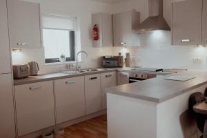 a white kitchen with white cabinets and a sink at Mews by the tay in Aberfeldy