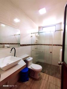 y baño con aseo, lavabo y ducha. en Hostal GalaHouse, en Puerto Ayora