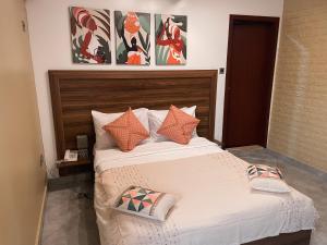 una camera da letto con un grande letto con cuscini arancioni di Sky Suites Osu a Accra