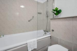 a bathroom with a tub and a toilet and a shower at Mansion House Flat by MySquare in London