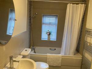 a bathroom with a sink and a toilet and a tub at Guest Homes - Hunters Wood Court in Euxton