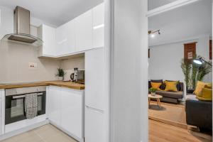 a kitchen with white cabinets and a living room at Mansion House Flat by MySquare in London
