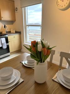 a vase of tulips on a table in a kitchen at Island View - Spacious Two Bedroom Oban Apartment with Sea Views in Oban +52 photos