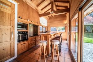 a kitchen with wooden cabinets and bar stools at Chalet L'aube claire - 5 étoiles in Morzine