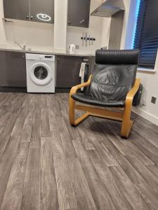 a chair in a laundry room with a washing machine at DE1 Studio Apartment Heart of City in Derby