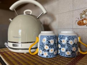 zwei Kaffeetassen auf einer Theke mit einer Teekanne in der Unterkunft Casa Margherita (Alba) in Alba