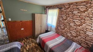 Un dormitorio con una pared de piedra y una cama. en Las palmeras de Colbún, en Colbún