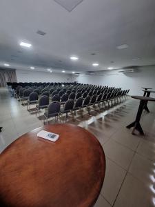 an empty room with chairs and a table and a book at Colonial Flat Hotel in Itapetininga