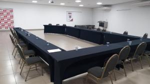a long black table and chairs in a room at Colonial Flat Hotel in Itapetininga