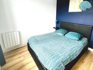 a bed in a bedroom with a blue wall at Charmant appartement proche des commerces et Gare in Saint-Brieuc