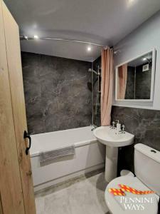 a bathroom with a sink and a toilet and a tub at Forge Cottage - Modern Cottage in Central Location in Haltwhistle