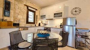 eine Küche mit einem Glastisch und einem Kühlschrank aus Edelstahl in der Unterkunft Maria's stone Heaven Retreat in Kalandra