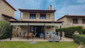 ein Haus mit einer Terrasse mit Tisch und Stühlen in der Unterkunft Maria's stone Heaven Retreat in Kalandra