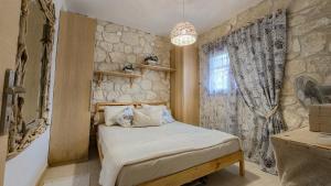 ein kleines Schlafzimmer mit einem Bett und einer Steinmauer in der Unterkunft Maria's stone Heaven Retreat in Kalandra