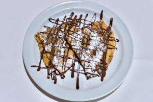 a white plate with a dessert with chocolate and whipped cream at Dunas Club - Hotel & Apartamentos in Corralejo