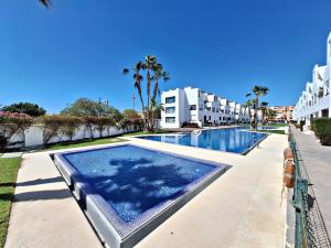 维拉Apartamentos Alborada III的棕榈树和建筑度假村的游泳池