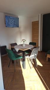 a dining room with a table and green chairs at Apartament Między górą a rzeką Trybsz in Trybsz