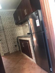 een keuken met een zwarte koelkast en houten kasten bij Mini villa duplex in Agadir