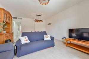 uma sala de estar com um sofá azul e uma televisão de ecrã plano em Apartment Beachfront 36 em Calpe