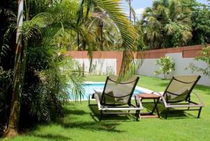 two chairs sitting in the grass next to a pool at Escalonia 2 in Las Terrenas