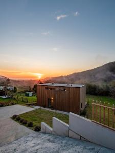 ein kleines Holzgebäude mit Sonnenuntergang im Hintergrund in der Unterkunft Doni Wood House, casa en la playa de Doniños in A Coruña