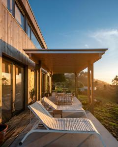 una terraza con sillas y mesas en un edificio en Doni Wood House, casa en la playa de Doniños, en A Coruña