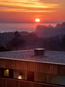 una vista de la puesta de sol desde el techo de un edificio en Doni Wood House, casa en la playa de Doniños, en A Coruña