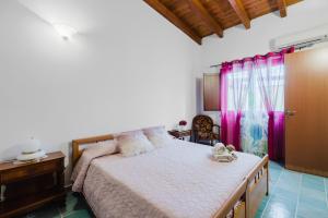a bedroom with a bed with pink curtains at Il Corbezzolo Apartment in Palmas Arborea