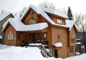 une maison en bois avec de la neige sur le toit dans l'établissement Chalets Alpins- 39 Chemin des Skieurs, à Stoneham