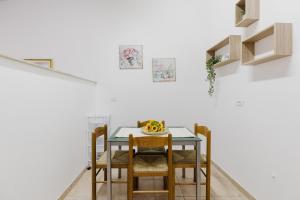 a dining room table with chairs and a bowl of fruit on it at Il Corbezzolo Apartment in Palmas Arborea +11 photos