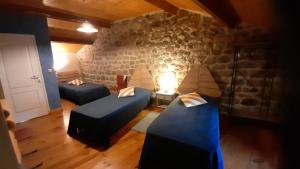 a room with two beds and a stone wall at Gîtes Le Triskèle in Rochepaule