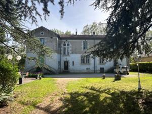 une grande maison blanche avec une voiture garée devant elle dans l'établissement Le Parc aux Cedres, à Laroque